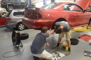 Senior Erik McIntosh is assisted by teacher Erik Falk as he rebuilds the brake system of a 1998 Ford Mustang. McIntosh bought the Mustang from the school for a reduced price as part of the student-sales program. “In addition, I flushed three fluid systems, brake, power steering and coolant as well as cleaning and buffing all the parts before I put them back on to make sure the car runs smoothly,” McIntosh said.