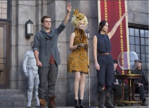 Peeta Mellark, played by Josh Hutcherson, and Katniss Everdeen, played by Jennifer Lawrence, raise their arms in salute to their home district after having their names drawn to participate in the 75th Annual Hunger Games. The Hunger Games: Catching Fire was filmed in 4K resolution and $130 million was spent on the film as a whole.