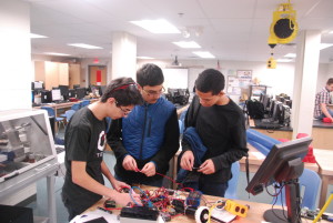 Freshman Kemal Ficici, sophomore Rishabh Jain and freshman Isaac Feldman work on building their robot after school in preparation for competition.