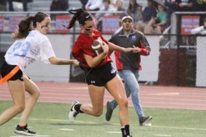Senior and powderpuff coach Demitri Gamble cheers on senior Haley Tonizzo as she runs into the endzone while dodging junior Carrie Eckert during the Powderpuff game on Oct. 11. 