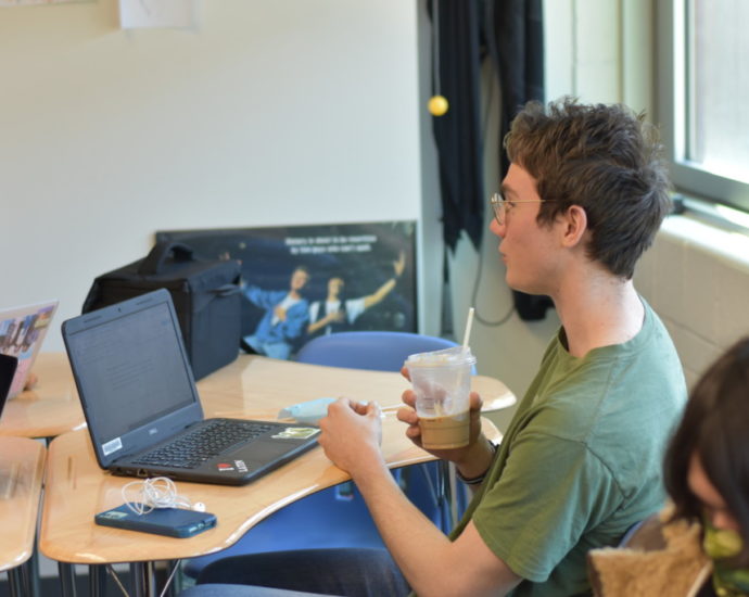 Junior Sam Peden drinks coffee and prepares for an exam in English teacher Matthew Horne’s class during Learn.